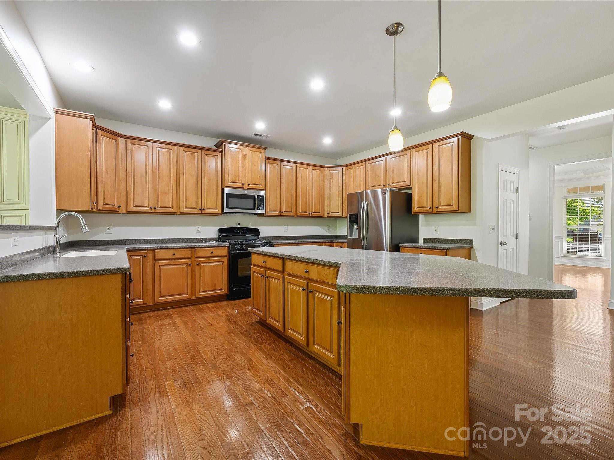 524 Becker Avenue Fort Mill, SC 29715 - Photo 19 of 39 a kitchen with stainless steel appliances granite countertop wooden cabinets a sink a stove a refrigerator and island with wooden floor