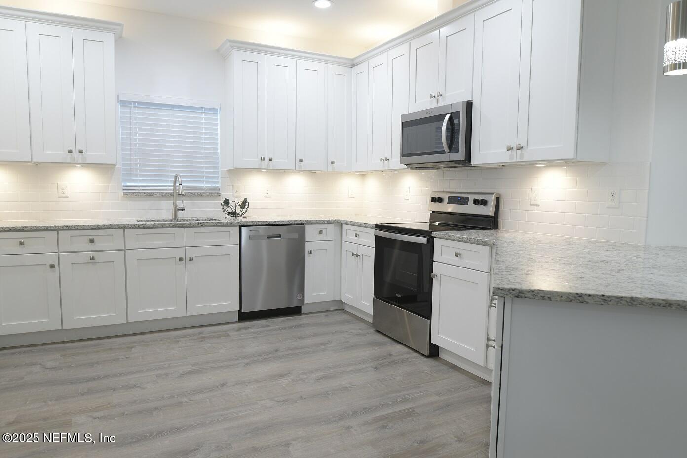 961 Calypso Way, Unit LOT 20 Jacksonville, FL 32233 - Photo 13 of 35 a kitchen with stainless steel appliances granite countertop a stove top oven a sink and white cabinets
