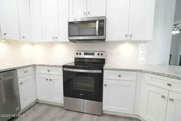 a kitchen with white cabinets and white appliances