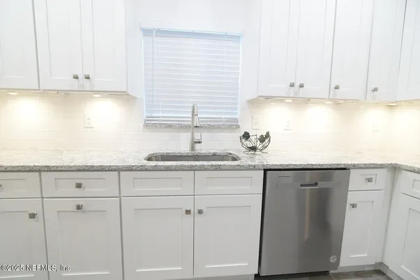 a kitchen with granite countertop white cabinets and a sink