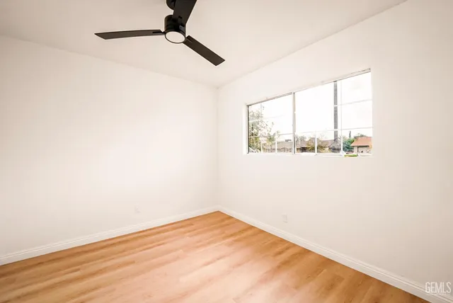 a view of empty room with wooden floor and fan