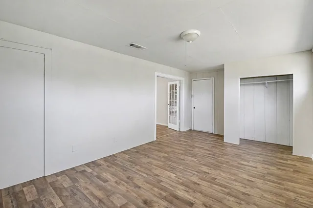 a view of an empty room with wooden floor and a closet