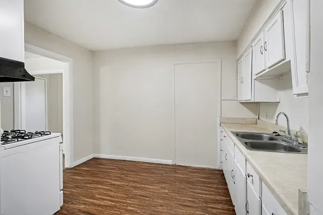 a kitchen with granite countertop a sink stove and cabinets