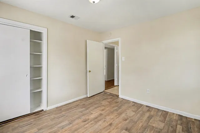 a view of an empty room with wooden floor and closet