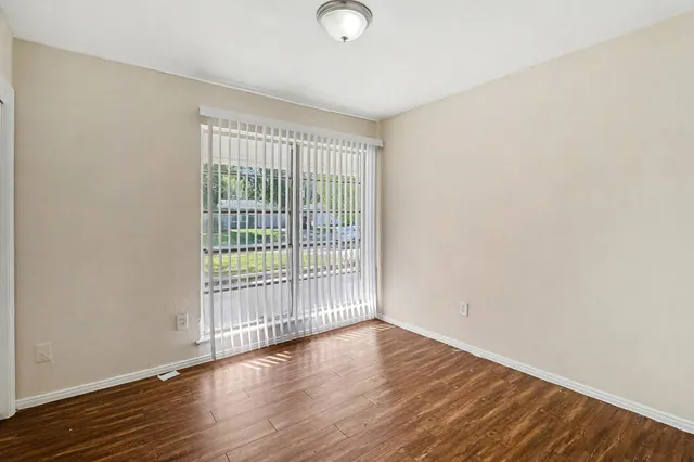 a view of an empty room with wooden floor and a window
