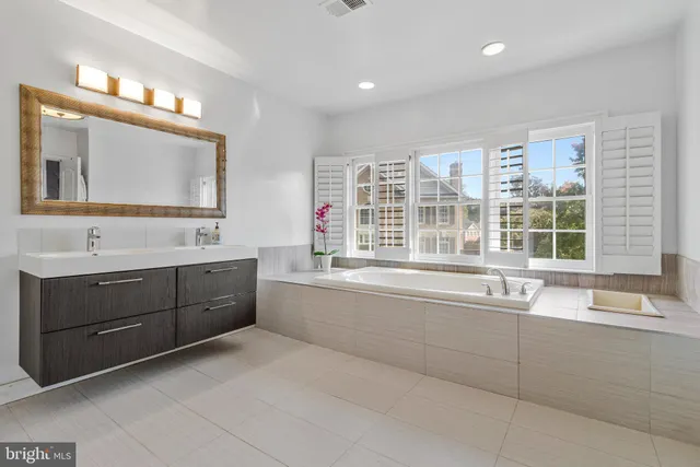 a bathroom with a double vanity sink bathtub and next to a window