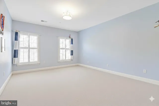 an empty room with windows and chandelier fan