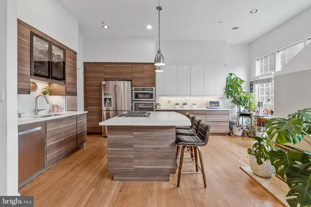 a kitchen with kitchen island a counter top space a sink stainless steel appliances and cabinets