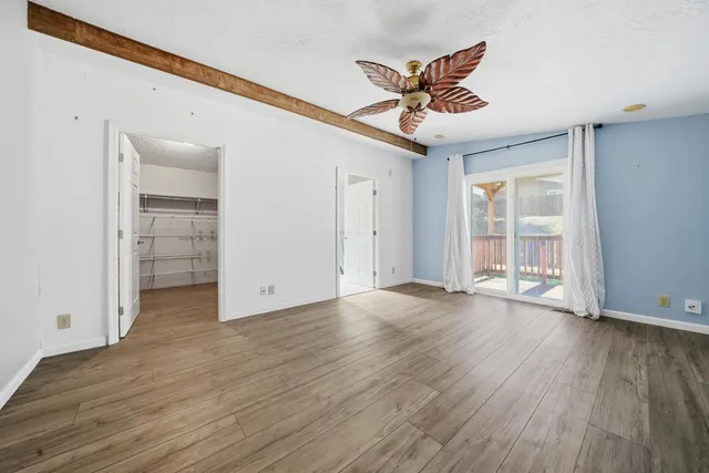 an empty room with wooden floor chandelier and windows