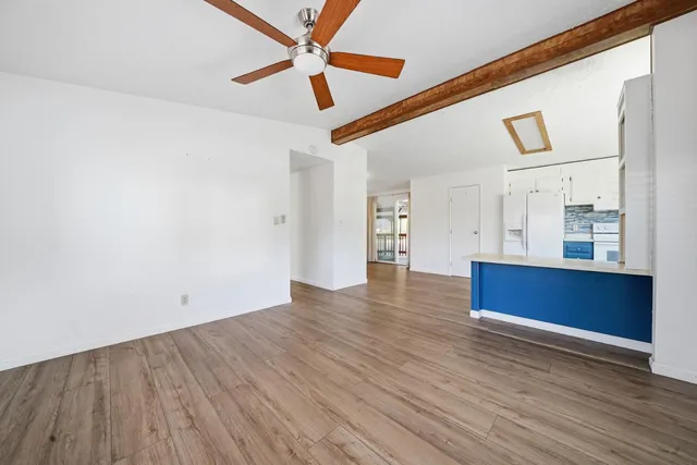 a view of an empty room with wooden floor and a ceiling fan
