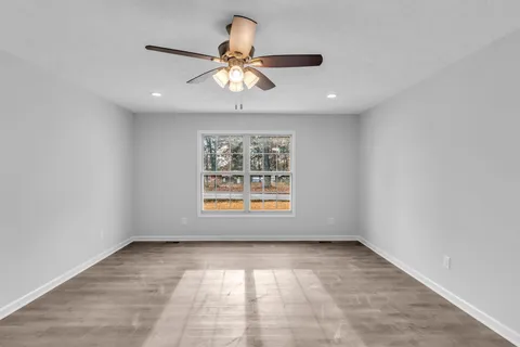 en empty room with windows and chandelier fan
