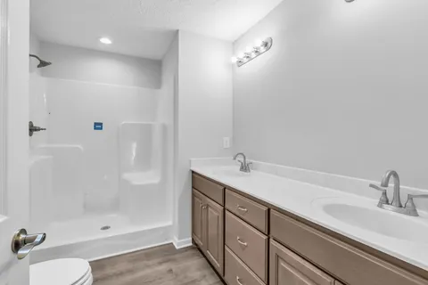 a bathroom with a shower sink vanity mirror and toilet