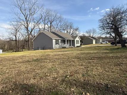 a front view of a house with a yard covered with trees