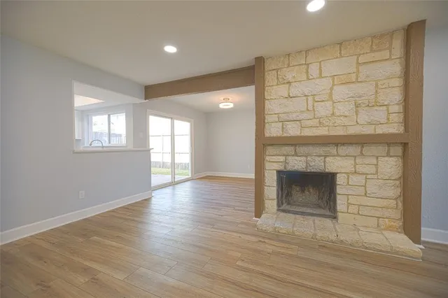 an empty room with wooden floor and fireplace