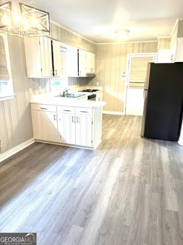 a large white kitchen with a sink wooden floor and a large window