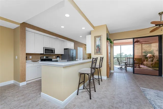 a kitchen with stainless steel appliances kitchen island granite countertop a refrigerator a stove a sink a dining table and chairs with wooden floor