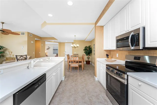a large white kitchen with stainless steel appliances granite countertop lots of counter space a sink and dishwasher a stove top oven a large window
