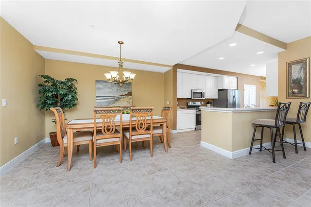 a dining room filled a chandelier and kitchen view