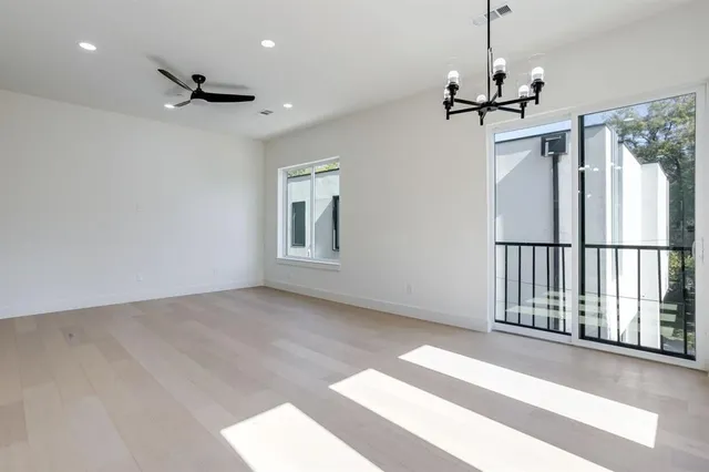 a view of empty room with wooden floor and ceiling fan