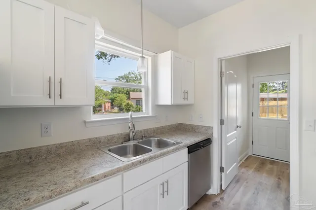 a kitchen with stainless steel appliances white cabinets and a wooden floor