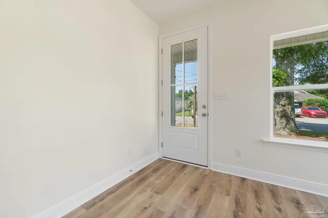 a view of an empty room with a window and wooden floor