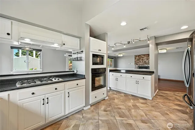 a kitchen with granite countertop a refrigerator and white cabinets