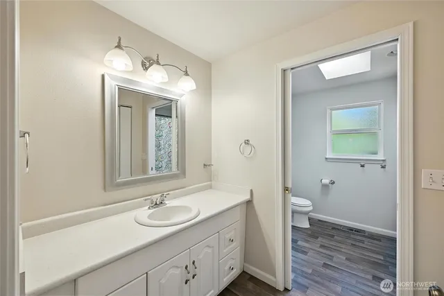 a bathroom with a toilet a sink a mirror and a window