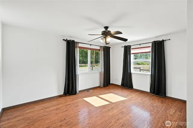 a view of empty room with wooden floor and fan