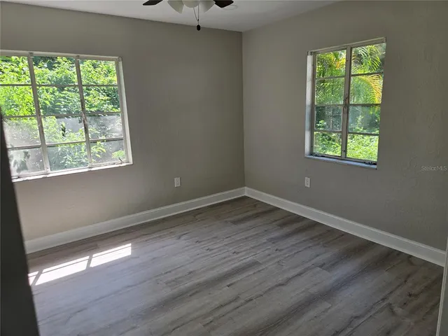 a view of an empty room with wooden floor and a window