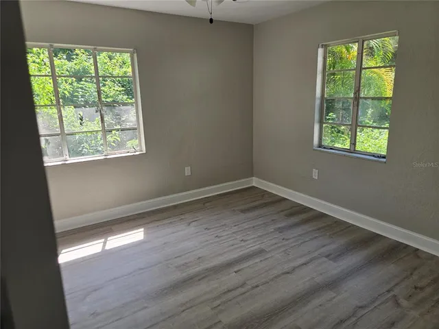 an empty room with wooden floor and windows