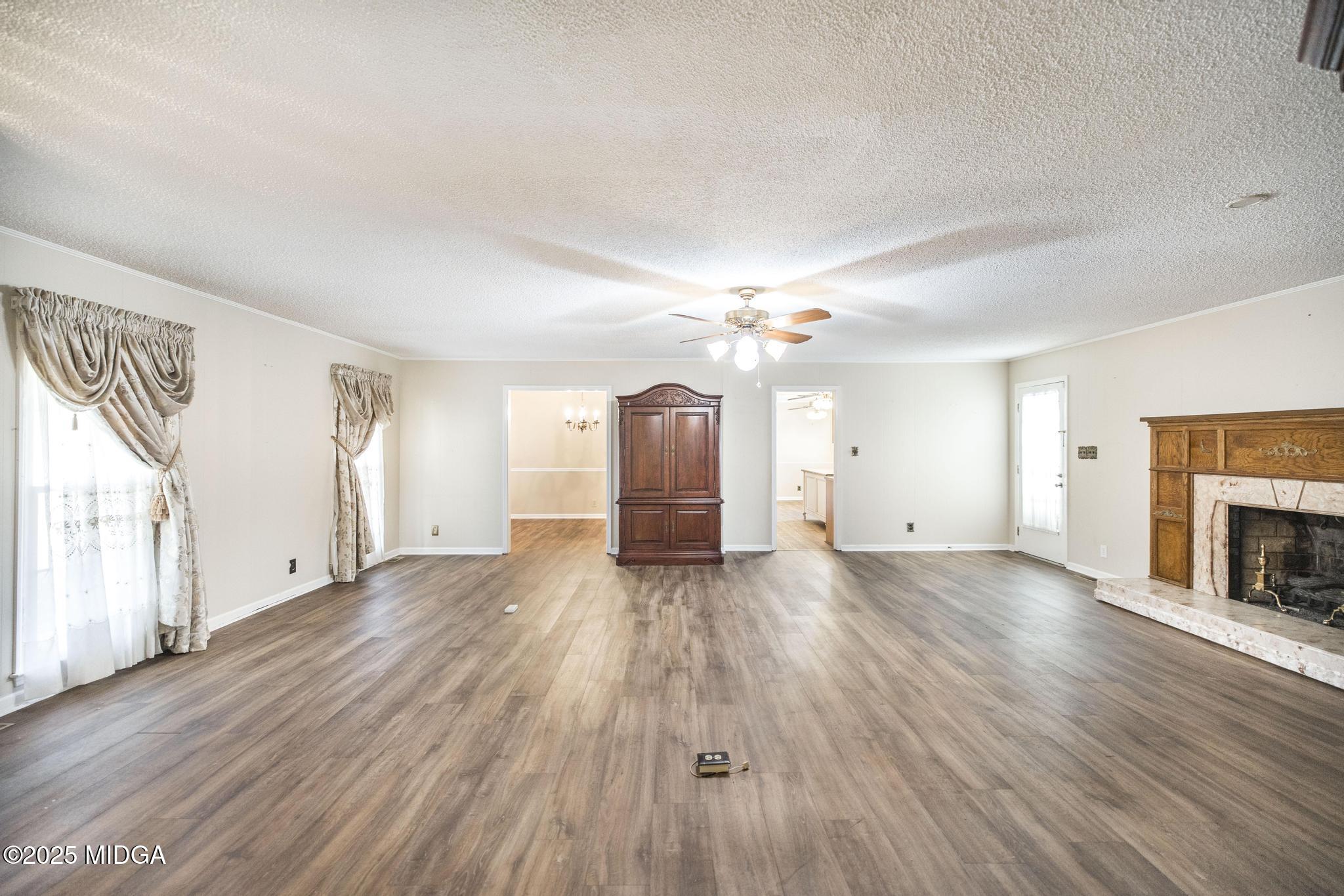 5812 Sardis Church Road Macon, GA 31216 - Photo 4 of 43 an empty room with wooden floor fireplace and windows