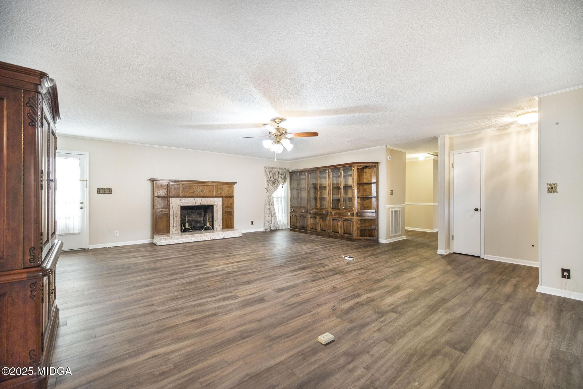 5812 Sardis Church Road Macon, GA 31216 - Photo 5 of 43 an empty room with wooden floor fireplace and chandelier