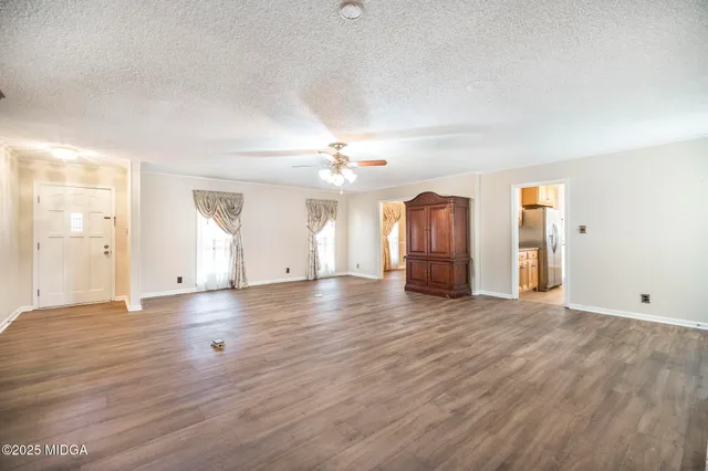 an empty room with wooden floor and windows