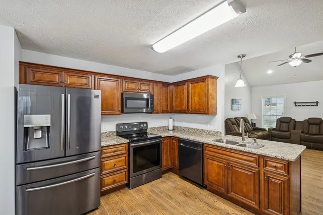 a kitchen with granite countertop a stove top oven microwave and refrigerator