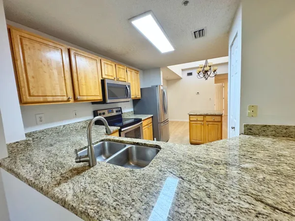 a kitchen with stainless steel appliances granite countertop a sink stove and refrigerator