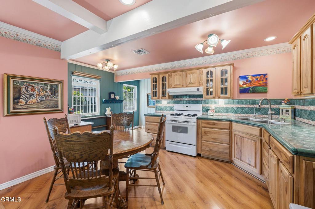 13934 Aztec Street Sylmar, CA 91342 - Photo 23 of 41 a kitchen with stainless steel appliances granite countertop a stove a sink dishwasher a dining table and chairs with wooden floor