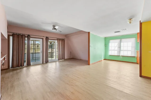 a view of an empty room with a window and wooden floor