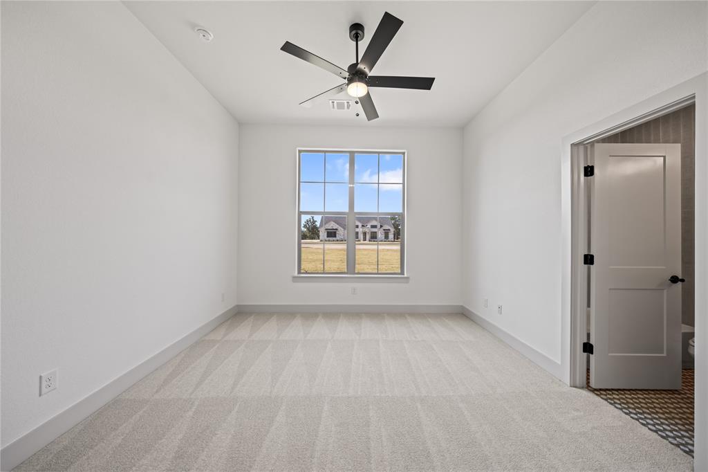 115 Red Bud Road Boyd, TX 76023 - Photo 31 of 38 Bright room featuring a large window, neutral carpeting, a ceiling fan with light fixture, white walls, and white trim