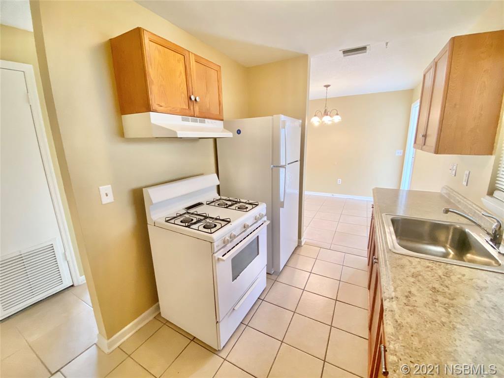 205 West Division Street DeLand, FL 32720 - Photo 4 of 15 a kitchen with a sink a stove and a refrigerator