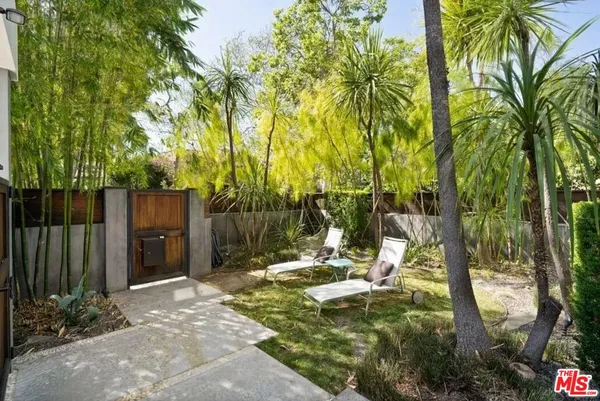 a backyard of a house with table and chairs under an umbrella