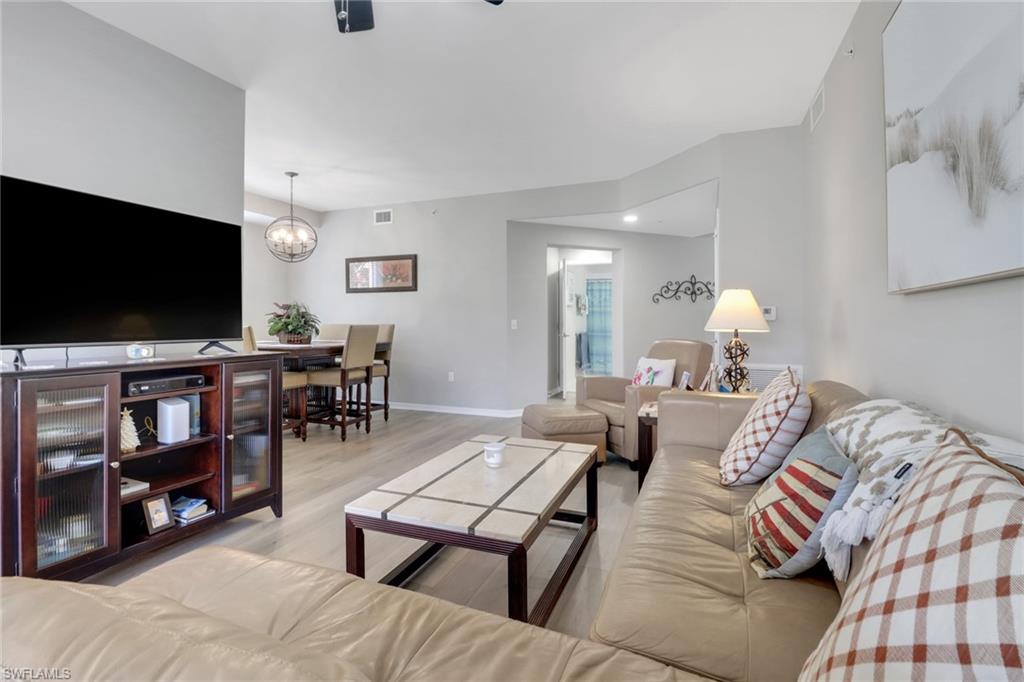 11601 Navarro Way, Unit 2102 Fort Myers, FL 33908 - Photo 11 of 25 Living area featuring light wood finished floors and a chandelier