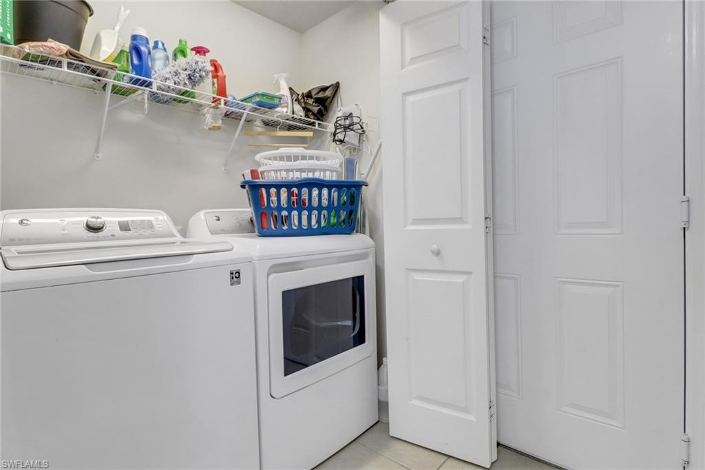 11601 Navarro Way, Unit 2102 Fort Myers, FL 33908 - Photo 21 of 25 Laundry room with light tile patterned floors and washing machine and clothes dryer