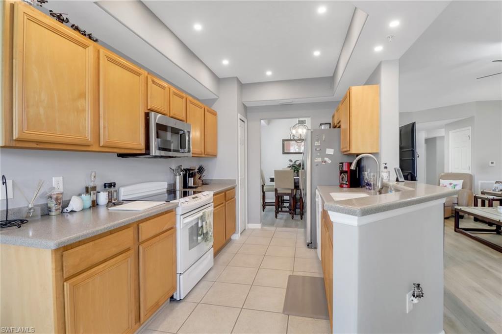 11601 Navarro Way, Unit 2102 Fort Myers, FL 33908 - Photo 3 of 25 Kitchen with white electric range oven, stainless steel microwave, light brown cabinetry, recessed lighting, and light tile patterned floors