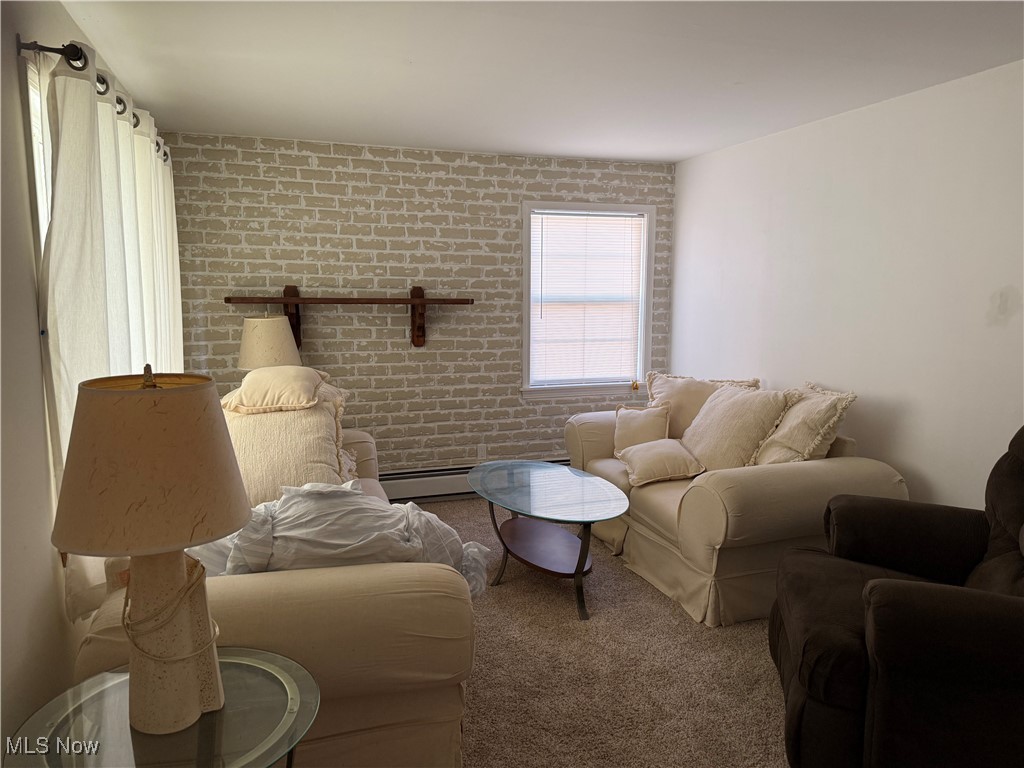1877 Clyde Road Madison, OH 44057 - Photo 7 of 19 Living area featuring brick wall, carpet, and baseboard heating