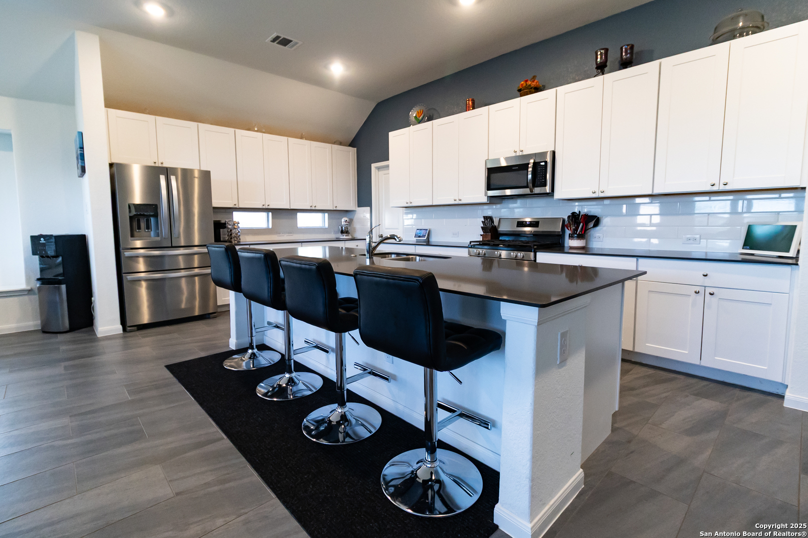 a kitchen with stainless steel appliances granite countertop a stove top oven a refrigerator a sink and a dining table with wooden floor