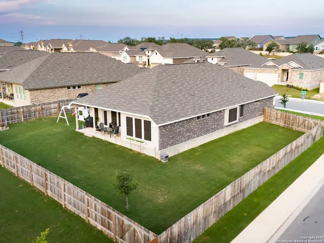 an aerial view of residential houses with outdoor space and trees