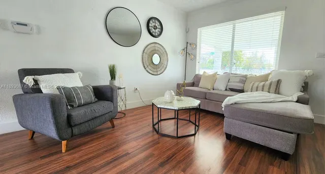 a living room with furniture a window and wooden floor