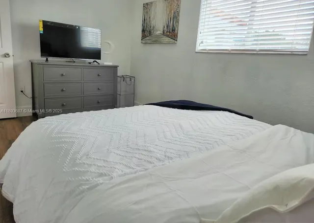 a bedroom with a flat screen tv and a window