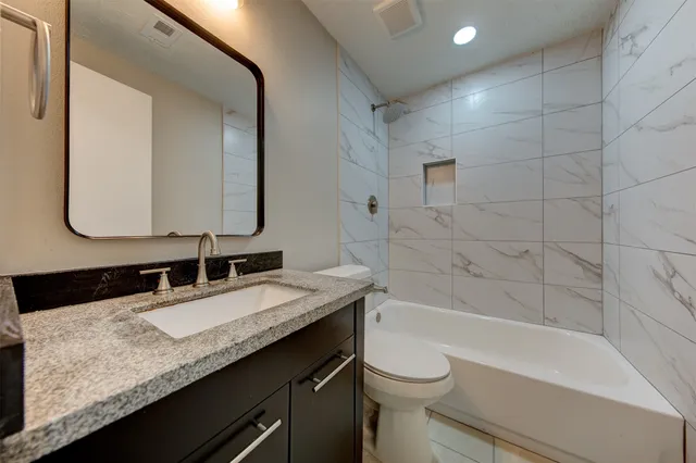 a bathroom with a granite countertop sink a toilet and bathtub