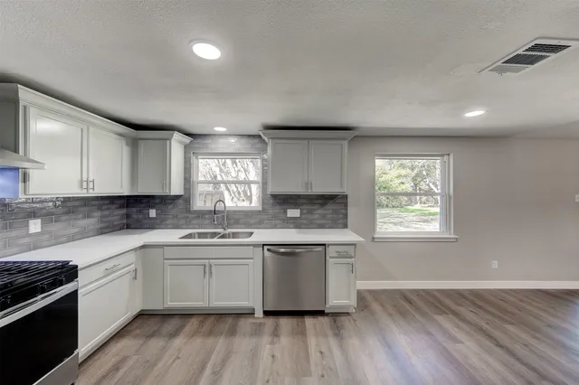 a kitchen with a sink cabinets wooden floor and stainless steel appliances